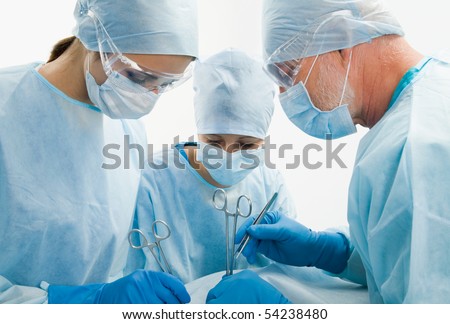 Group of surgeons looking at patient on operation table during their work