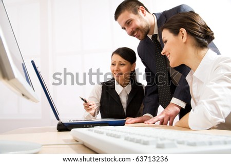 Portrait of executive employees looking at laptop monitor and discussing new project