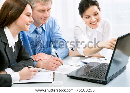 Successful businessman and his pretty colleagues looking at monitor of computer