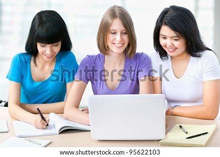 Three female friends studying together in a classroom