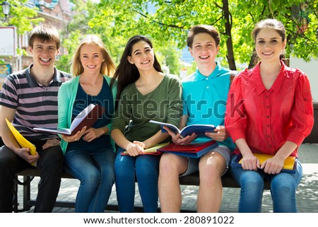 Group of university students studying, reviewing homework in park