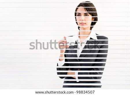 Business woman with cup of coffe looking through a venetian blind in an office