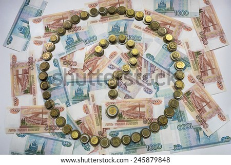 The question mark in the circle, made of coins on the background of banknotes of Russia .