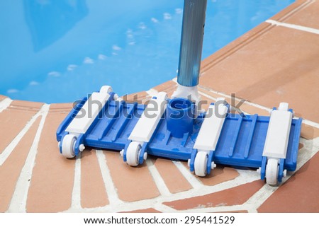Wall Brush and Leaf Skimmer Maintenance Tools on Deck Beside Swimming Pool