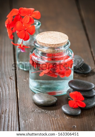 Spa stones and glass jar with red flowers
