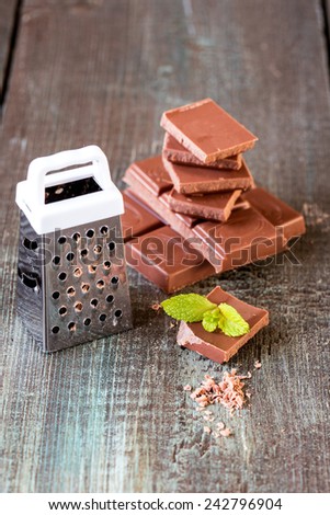 stack of chocolate pieces with a leaf of mint on wooden background