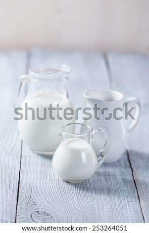 Three milk jars on white wooden white background