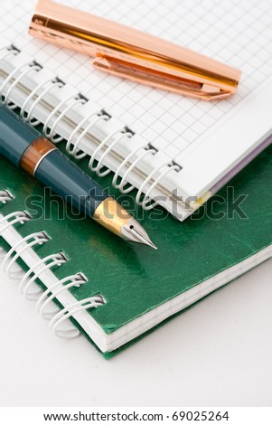 The ink pen lying on a green notebook isolated on a white background