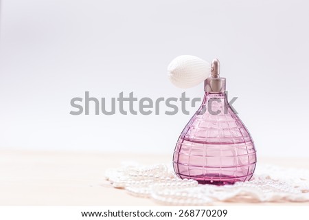 Pink glass bottle of female perfume and Pearl beads. Soft toning.