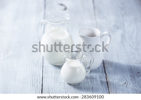 Three milk jars on white wooden background