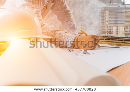 Architect working on blueprint. Architects workplace - architectural project, blueprints, ruler, helmet and divider. Construction concept. Engineering tools