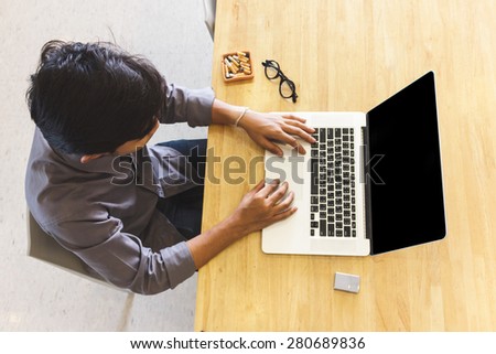 image of top view young business man is using laptop while siting on the wooden chair