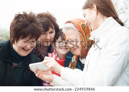Laughing people look at mobile phone. Emotional group portrait. Women of all ages
