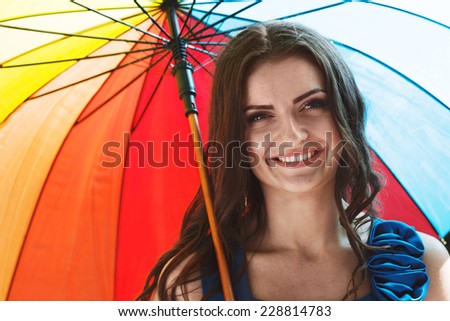 Girl under umbrella. Emotional portrait of beautiful smiling brunette. Pleasant emotions, happy mood. Colors of rainbow