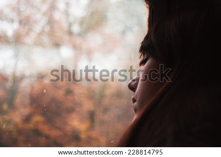 Girl sleeping in train. Portrait of beautiful brunette. Journey by rail. Fall outside window, autumn colors
