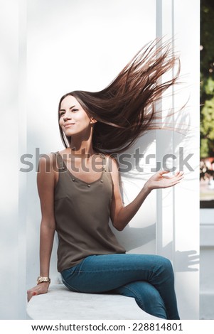 Girl wave her hair. Emotional portrait of beautiful brunette. Beautiful lush hair. Pleasant emotions, happy mood. City street