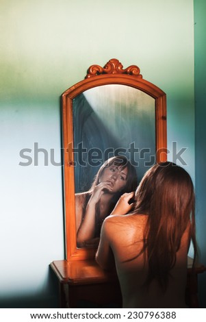 Girl and mirror. Portrait of beautiful naked brunette with reflection in mirror