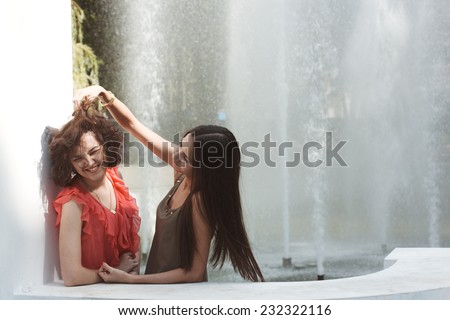 Best friends. Emotional portraits of beautiful brunettes. Pleasant emotions, happy mood. Female friendship. City fountain