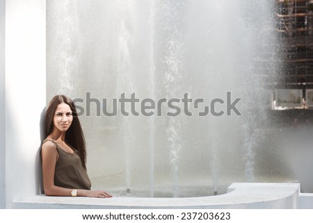 Girl in city. Emotional portrait of beautiful brunette. Pleasant emotions, happy mood.  City fountain