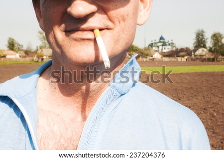 Cigarette in mouth. Portrait of smiling man. Bad habit, addiction, problems with health