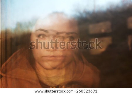 Portrait of girl, reflected in window of train. Optical effect. Fall outside window