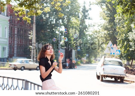 Girl and soap bubbles. Smiling girl playing with soap bubbles on city street