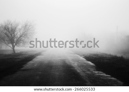 Man in fog. Silhouette of man walking on misty village road. Loneliness, nostalgia, sad mood. Black and white photo