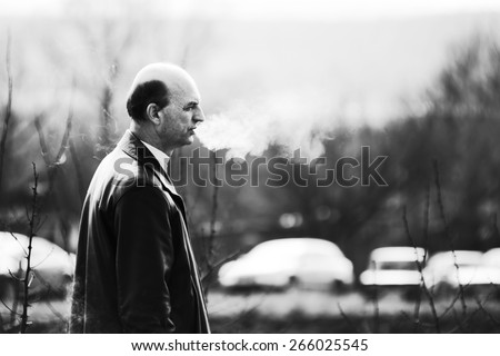 Smoking man. Man smoke and exhaled smoke. Black and white photo