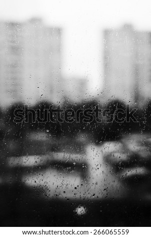 Drops of rain. View on city street through window in rain. Rainy weather. Sad mood. Black and white photo