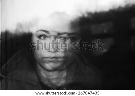 Portrait of girl, reflected in window of train. Optical effect. Fall outside window. Black and white photo
