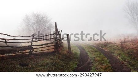 Rural landscape with road and fence. Wooden fence and tree in  fog. Spring morning. Loneliness, sad mood
