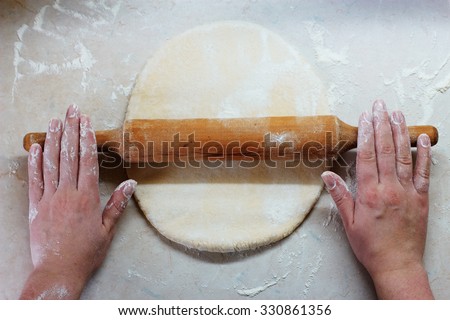Sheeting dough. Women\'s hands are holding rolling pin and floured. Baking in kitchen. Chef at work
