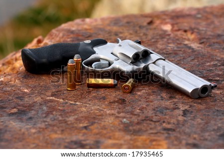 44 caliber hand gun laying on the rad stone with cartridges