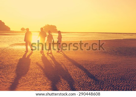 The family walking at the beach during sunset time, orange sun light, like instagram filter effect