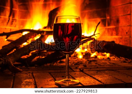 Glass of wine standing by the fireplace on a background of fire flame