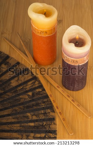 Zen candles, black lace fan and asian bamboo chopsticks on bamboo background