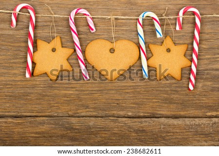 Christmas ornament - gingerbread, candy cane, rope with wood hooks on old wooden background