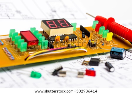 Workbench for interphone electronics repair, electronic diagram, multimeter, electronic components, electronic board, screwdrivers, transistors, integrated circuits, capacitors, LED