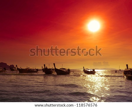 Sea coast landscape nature background, fishing boats silhouettes at evening  Red sunset with warm sun rays and dark ocean water.