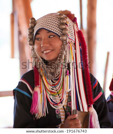 CHIANG RAI, THAILAND - DEC 4, 2013: Unidentified Akha girl in traditional clothes and silver jewelery in akha hill tribe minority village near Chiang Mai. Famous tourist destination.