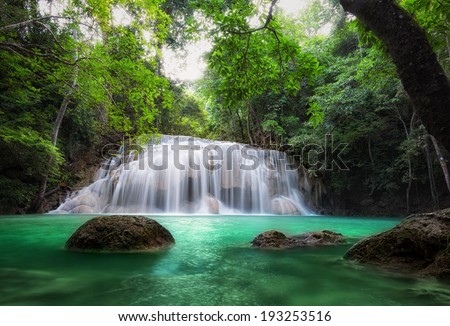 Waterfall in tropical forest. Beautiful nature background. Jungle trees and blue water of mountain river in national park in Thailand, Asia