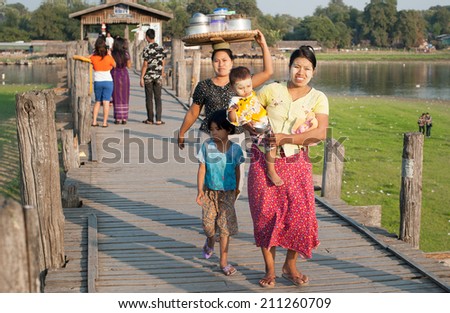MANDALAY, MYANMAR - JAN 19, 2014: Unidentified local citizens of Amarapura crossing U Bein bridge located on Taungthaman Lake. Bridge is believed to be the oldest and longest teak bridge in the world