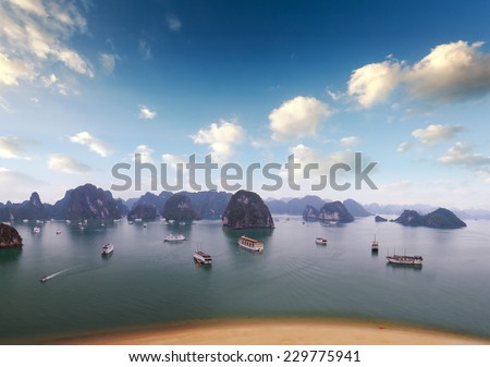 Halong Bay Vietnam. Boats, junks and tourist ships cruise. Holiday vacation destination background. Sandy beach, islands and blue sky with clouds