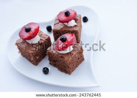Brownies with fruits and cream on a heart shaped plate