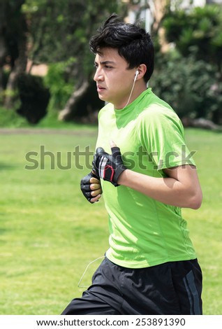 Young man at a local green park jogging (vertical)