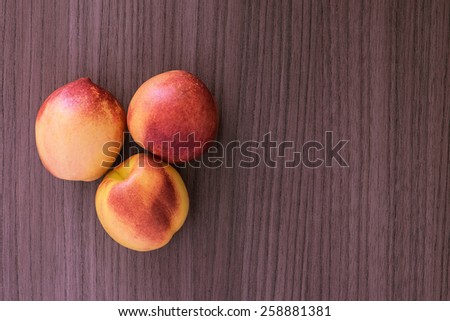 Three succulent red and yellow peaches over wood