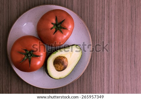 A dish with two big tomatoes and half avocado