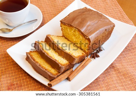 Cup of tea and cake with glaze of chocolate and spices  in the white dish. Selective focus