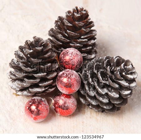 three snow-covered pine cones and red Christmas balls