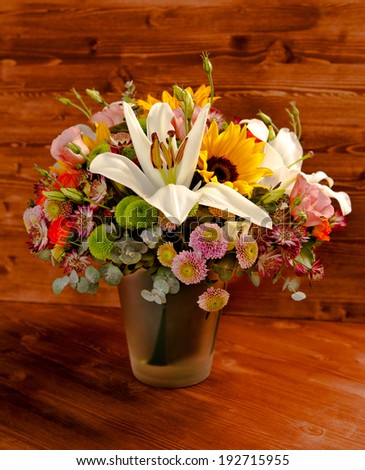 floral bouquet with lily, sunflower, chrysanthemum, eustoma (lisianthus) astrantsiya, eucalyptus, shrub rose on wooden board